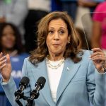 Woman speaking at a podium, gesturing with hands.