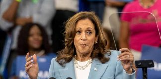 Woman speaking at a podium, gesturing with hands.