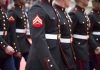 Marines in uniform standing in line, American flags displayed.