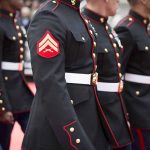 Marines in uniform standing in line, American flags displayed.