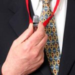 Person holding a whistle on a red lanyard.