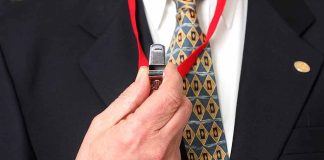 Person holding a whistle on a red lanyard.