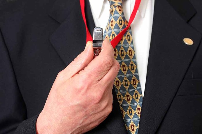 Person holding a whistle on a red lanyard.