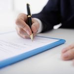 Person signing a document with a pen.