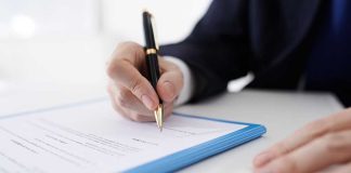 Person signing a document with a pen.