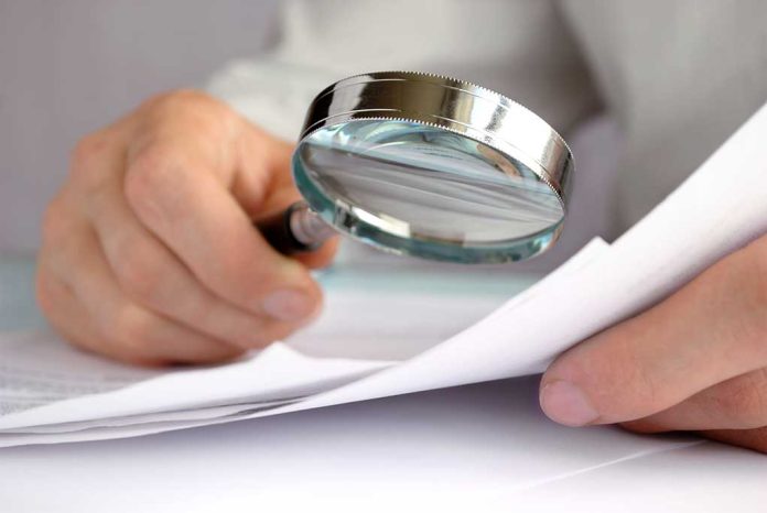 Person examining documents with a magnifying glass.