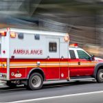 Red and white ambulance driving on street.