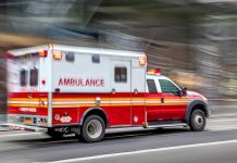 Red and white ambulance driving on street.