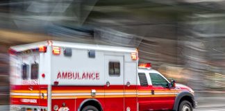 Red and white ambulance driving on street.