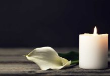 White candle and calla lily on wooden surface.