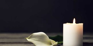 White candle and calla lily on wooden surface.