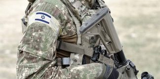 Soldier in camouflage gear with Israeli flag patch.