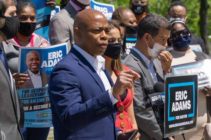 Man speaking at campaign event with supporters behind him.