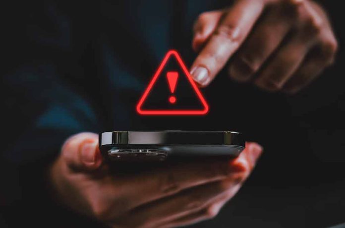 Finger touching phone with red warning symbol.