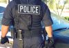 Police officer in uniform standing near a patrol car.