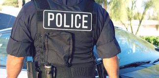 Police officer in uniform standing near a patrol car.