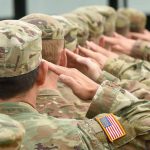 Soldiers in uniform saluting, American flag patch visible.