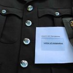 Police uniform with a resignation letter.