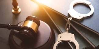 Gavel, books, and handcuffs on a table.