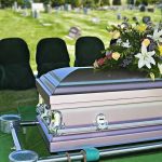 Casket with floral arrangement in a cemetery.