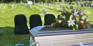 Casket with floral arrangement in a cemetery.