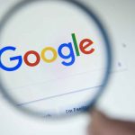 Google logo viewed through a magnifying glass.