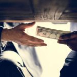 Hands exchanging money under a table.