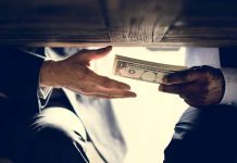 Hands exchanging money under a table.