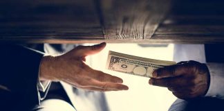 Hands exchanging money under a table.