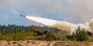 Military tank firing a missile in forest area.