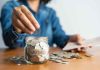 Person adding coins to a savings jar