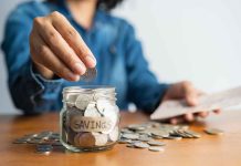 Person adding coins to a savings jar