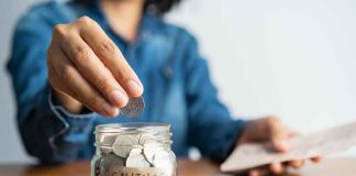 Person adding coins to a savings jar