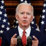 Man speaking at podium with American flags behind