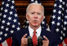 Man speaking at podium with American flags behind