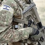 Soldier in camouflage gear with Israeli flag patch.