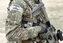 Soldier in camouflage gear with Israeli flag patch.