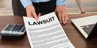 Person holding lawsuit document at desk with laptop