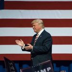 Man clapping near American flag at event