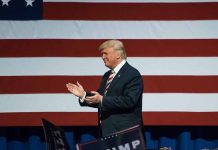 Man clapping near American flag at event