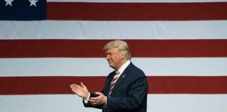 Man clapping near American flag at event