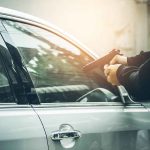 Person pointing gun at a car window.