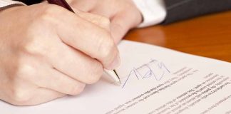 Hand signing a document with a pen