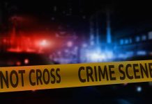 Crime scene tape with blurred police lights background.