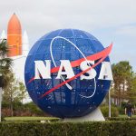 Blue NASA globe with rocket in background.