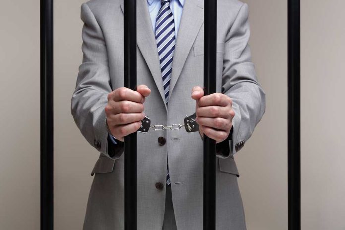 Person in handcuffs wearing suit behind bars