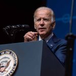 Man speaking at podium with presidential emblem visible