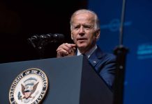 Man speaking at podium with presidential emblem visible