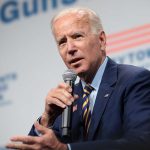 Man in suit speaking into microphone at event