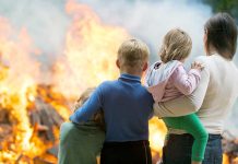 People watching large outdoor fire together